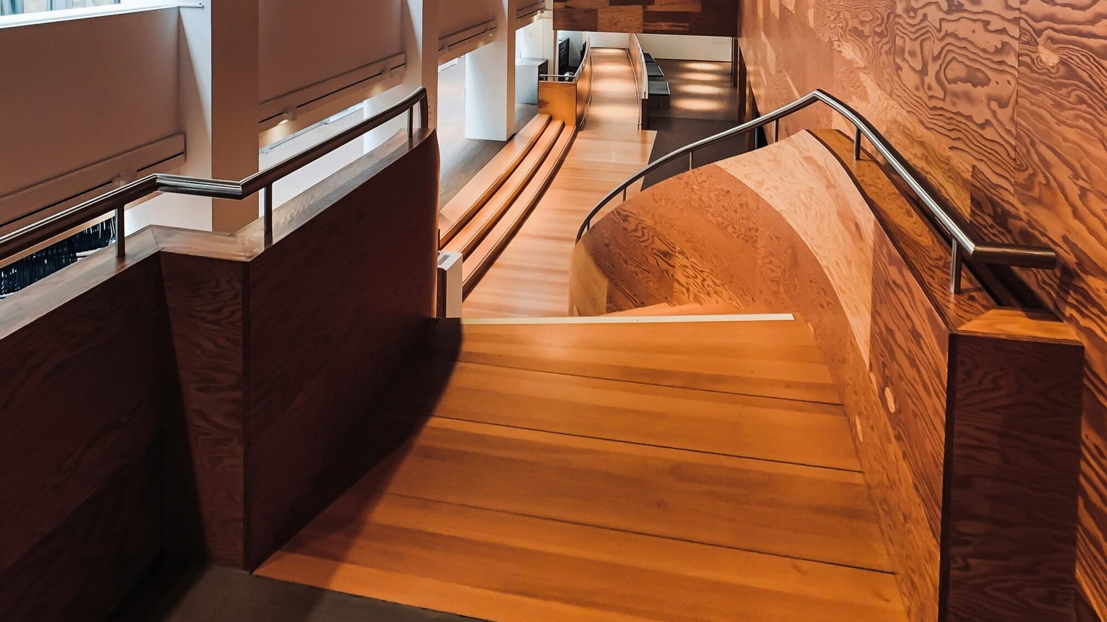 Curved custom hardwood staircase with wood-paneled walls
