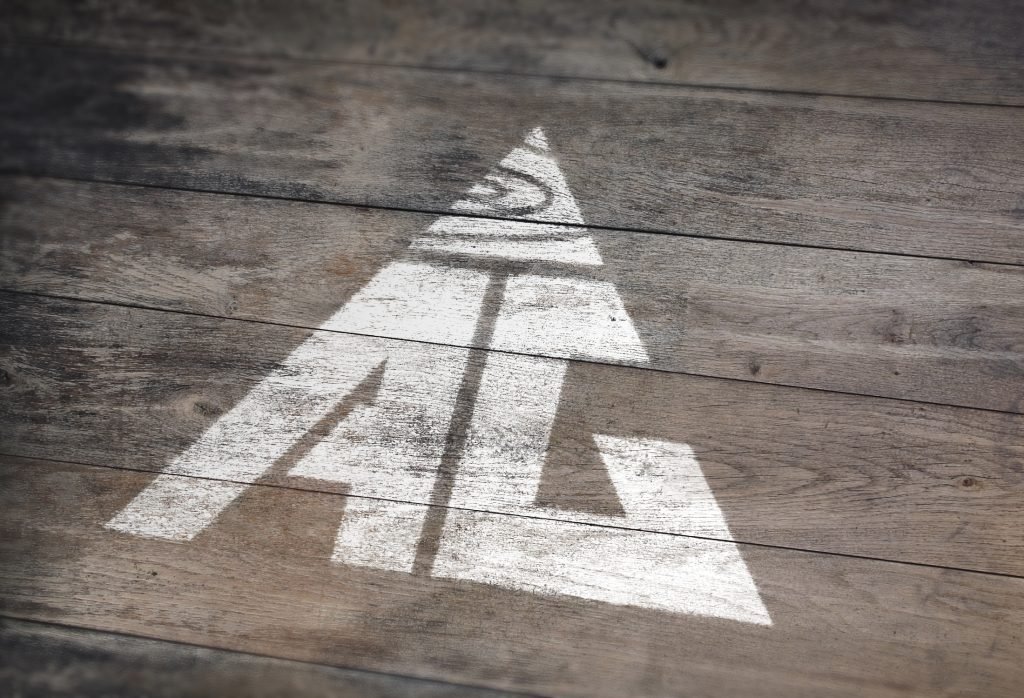 AG Floor Covering logo stenciled on a weathered grey hardwood floor